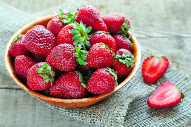 Fresh strawberries in a bowl on wooden surface