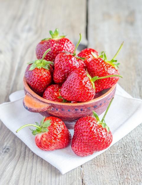 Fresh strawberries in the bowl on the wooden table