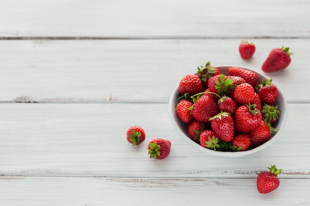 Fresh strawberries on ceramic bowl, top view