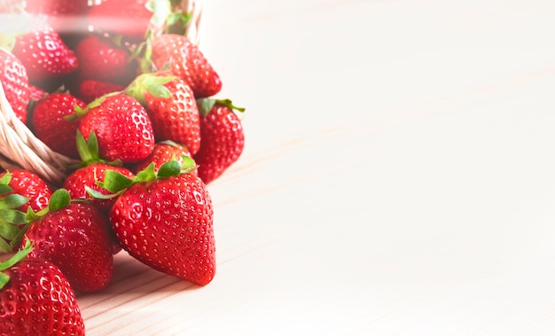 Fresh strawberries falling on a wooden table with copy space and illuminated by sunlight