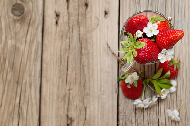 Fresh strawberries in a glass cup on a wooden table