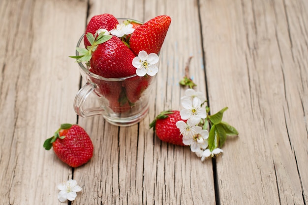 Fragole fresche in una tazza di vetro su una tavola di legno