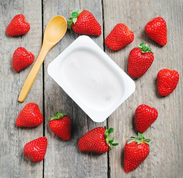 Fresh strawberries and milk yogurt on wooden table
