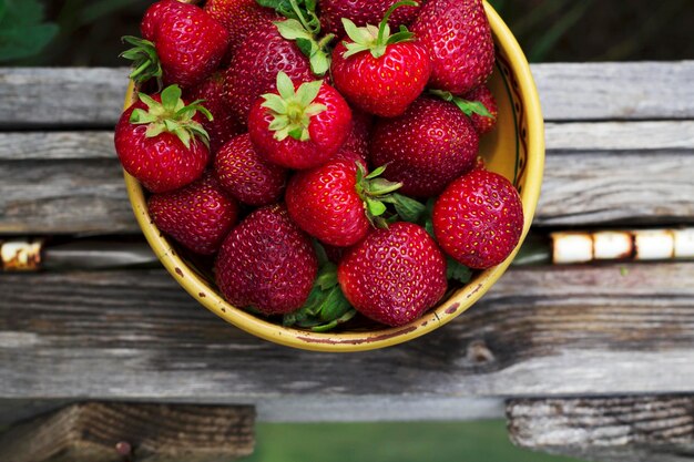 Fragole fresche nella vecchia ciotola di ceramica con vista dall'alto nel giardino