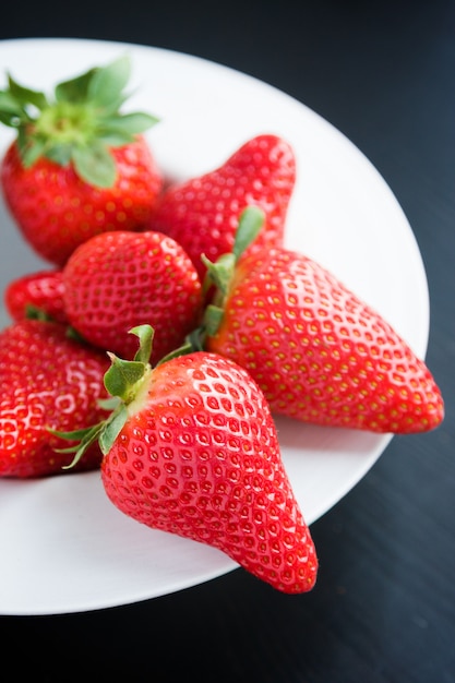 Fresh strawberries on plate on black background