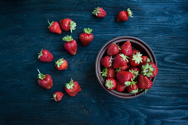 Fresh strawberries in a plate on a dark wood