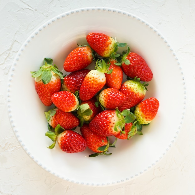 fresh strawberries on the white plate, top view