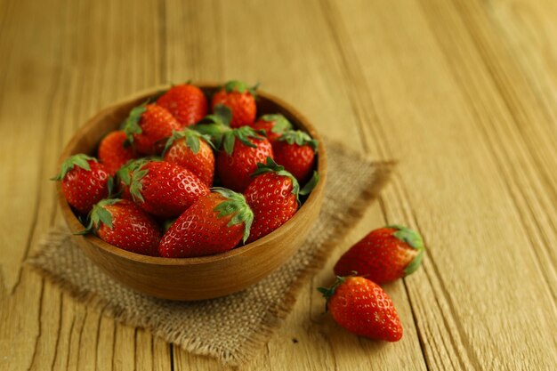 Fresh strawberries in a wooden bowl on wooden table