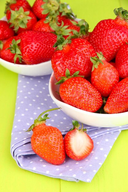 Fresh strawberry in bowl on green wooden background