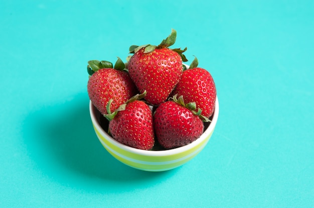 Fresh strawberry in a cup on green and yellow background. Creative strawberry, flat lay