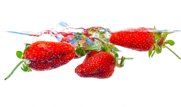 Fresh strawberry dropped into water with splash on white backgrounds