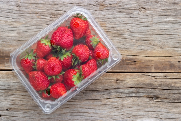 Фото Свежая клубника в пластиковой коробке. полезные и сладкие фрукты.