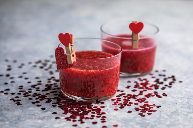 Fresh strawberry margarita or daiquiri cocktail with hearts over gray background, valentine day concepts