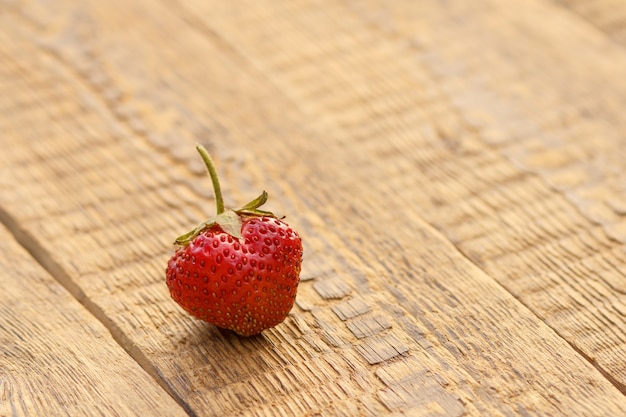 Fresh strawberry on old wooden surface. Sweet ripe strawberry on rustic wooden boards.