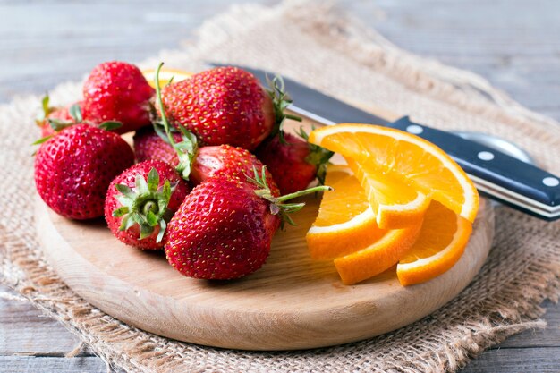 Fresh strawberry and orange on a wooden board