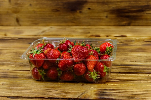 Fresh strawberry in plastic box on a wooden table