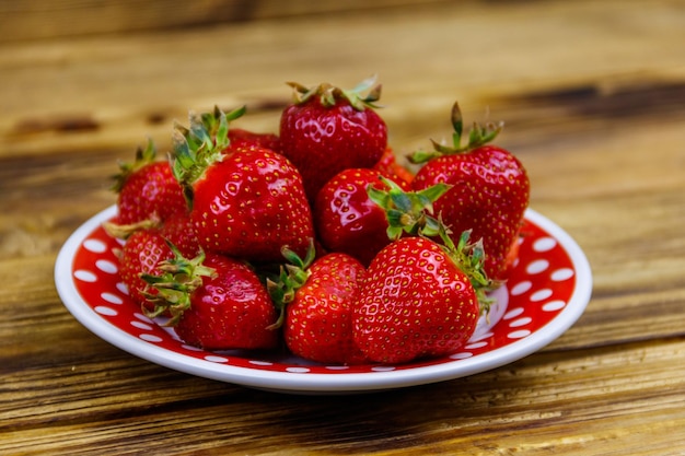 Fresh strawberry in a plate on a wooden table