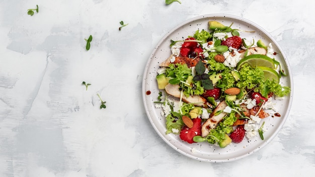 Insalata di fragole fresche con carne di pollo avocado, feta, lattuga e noci aceto balsamico. delizioso concetto di cibo equilibrato. formato banner lungo. vista dall'alto.