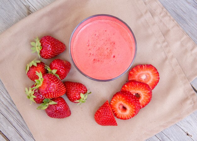 Fresh strawberry smoothie juice and strawberries on a napkin top view