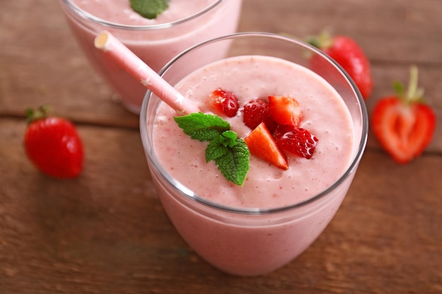 Foto yogurt alla fragola fresco con frutti di bosco intorno su fondo di legno