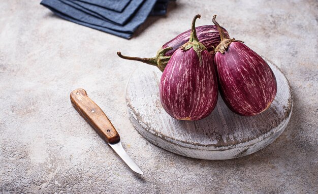 Fresh striped purple aubergines on light background