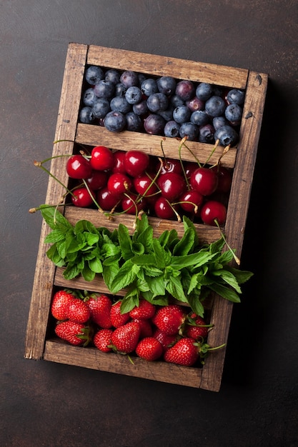 Fresh summer berries box Cherry blueberry strawberry and mint Top view