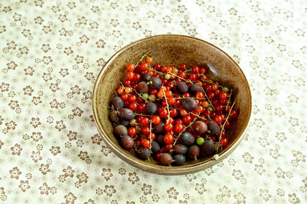 Фото Свежие летние ягоды в тарелке красная смородина и крыжовник из сада. фото высокого качества