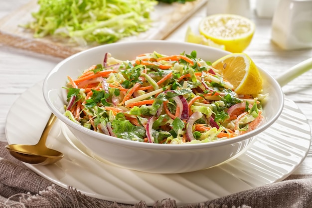 fresh summer coleslaw salad with light yogurt dressing in a white bowl on a textured wooden table,  close-up