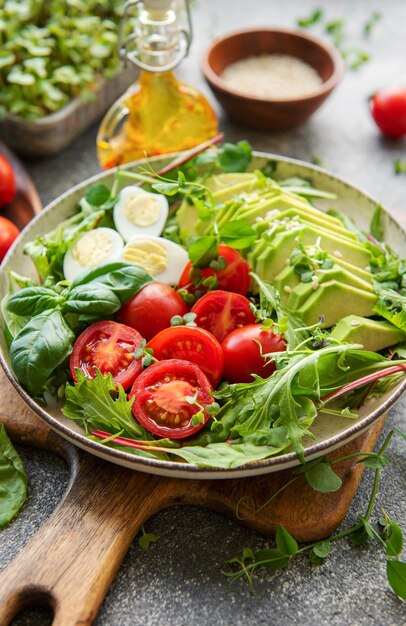 Fresh summer salad with arugula red cherry tomatoes basil eggs and avocado vegan food