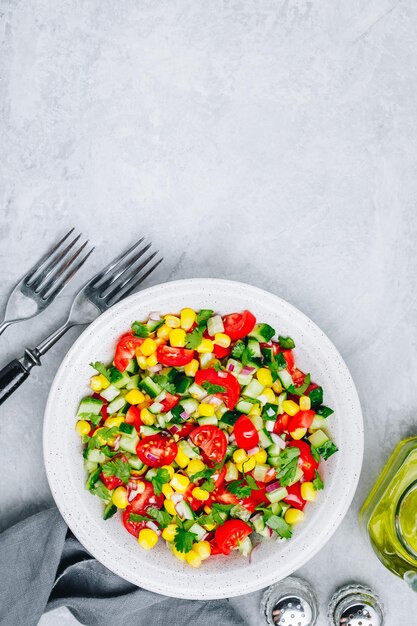 Fresh summer sweet corn salad bowl with tomatoes cucumbers red onions and parsley Top view