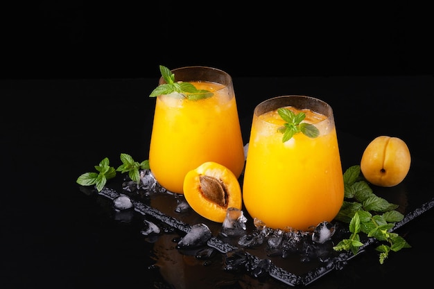 Fresh sweet apricot juice and mint on a black background