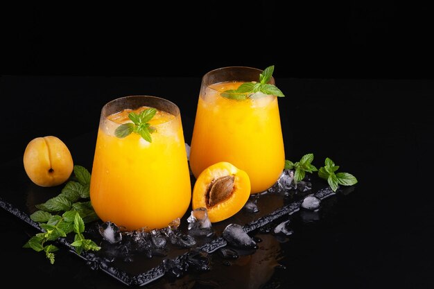 Fresh sweet apricot juice and mint on a black background