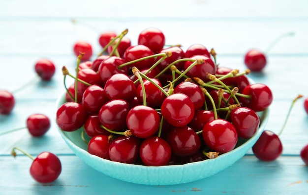 Fresh sweet cherries bowl on blue background Top view