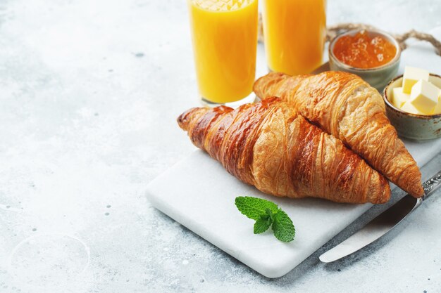 Croissant dolci freschi con burro e marmellata di arance per colazione.