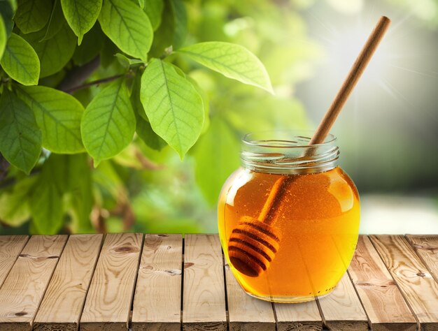 Fresh sweet honey with wooden honey dipper in glass jar