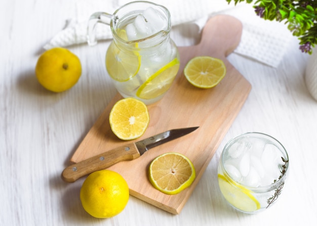 Свежая сладкая лимонадная вода; нож, дерево и некоторые растения