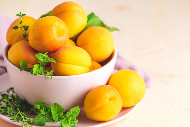 Fresh sweet orange apricots in pink bowl on the pink concrete surface table selective focus shallow depth of the fields