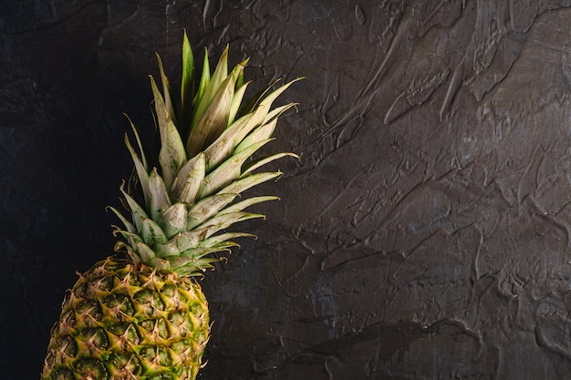 fresh sweet pineapple on dark black textured surface, top view copy space