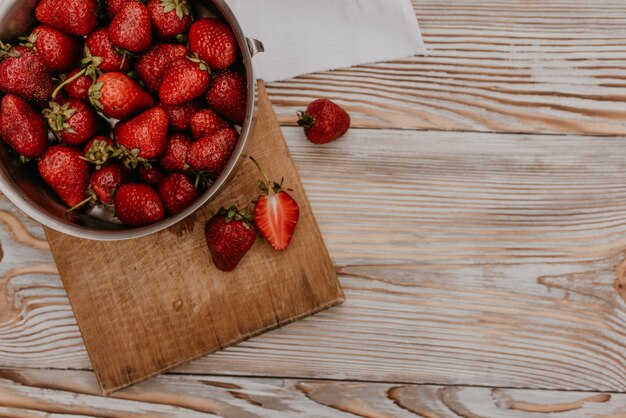 Fresh sweet ripe red strawberries lie in a metal stainless stewpan