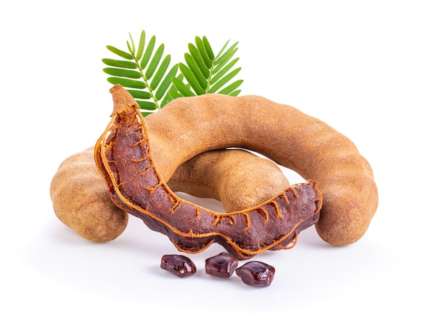 Fresh tamarind fruits and leaves on white wall. 