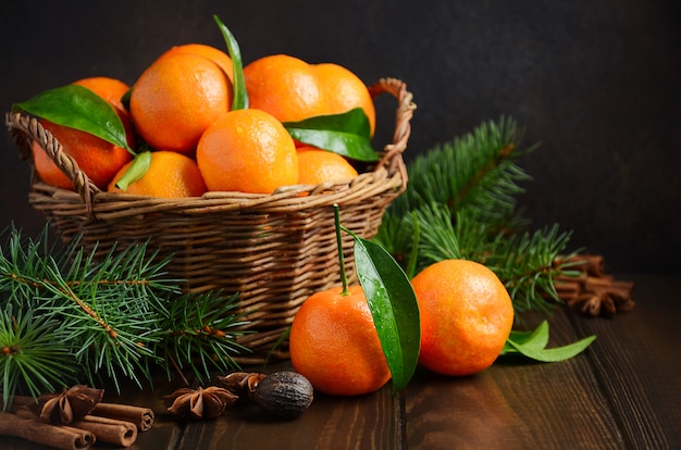 Fresh tangerine clementines with spices on dark wooden background