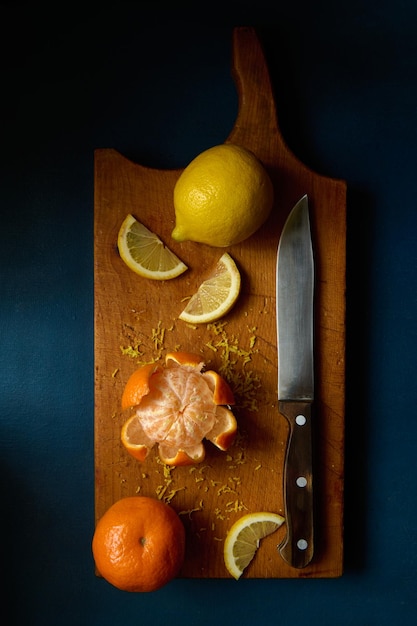 Foto mandarino e limone freschi che si trovano su un tagliere di legno che cucina profondità di campo poco profonda