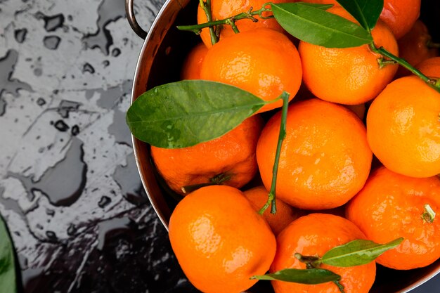 Fresh tangerines in the basket on a Black Background. Citrus background. Wet. Macro