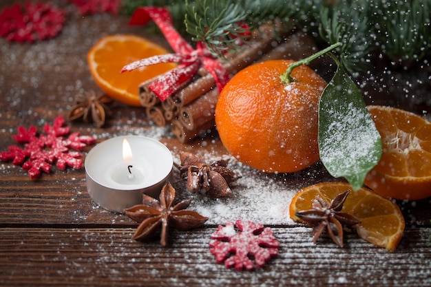 Fresh tangerines burning candles and fir tree branches on wooden table