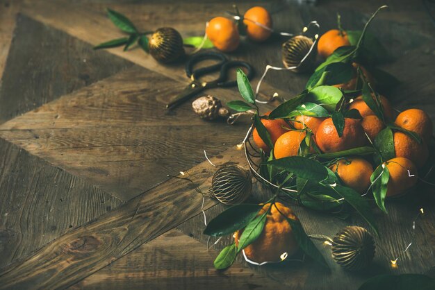 Fresh tangerines decoration toys and light garland over rustic background