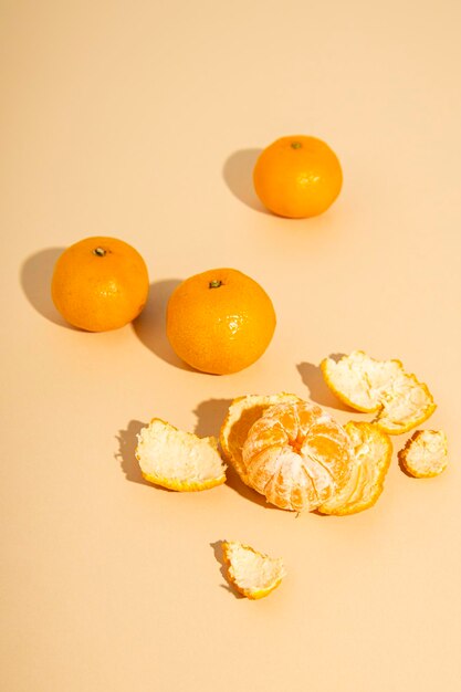 Fresh tangerines one peeled tangerine on a beige background Top view flat lay