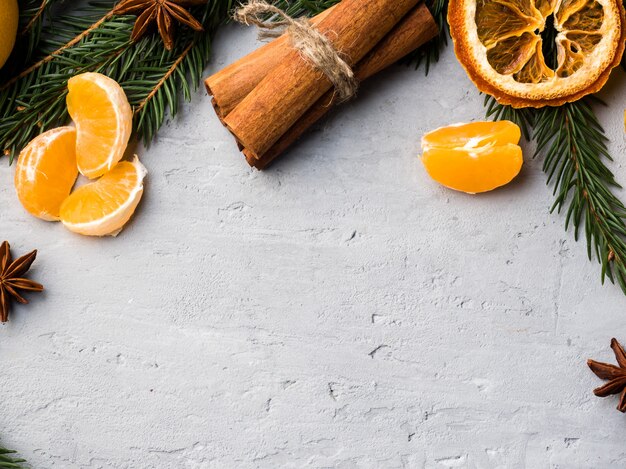 Fresh tangerines with branches of Christmas tree, star anise cinnamon on gray concrete, copy space