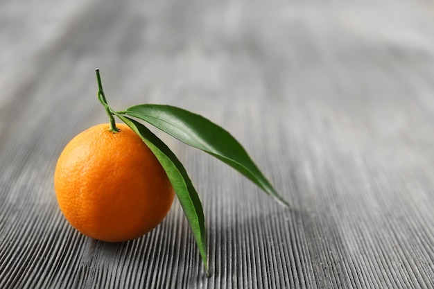 Fresh tangerines with leaves on wooden table, closeup