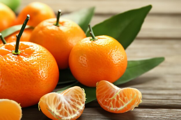 Fresh tangerines with leaves on wooden table closeup