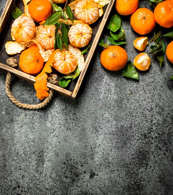 Fresh tangerines on a wooden tray on a rustic background